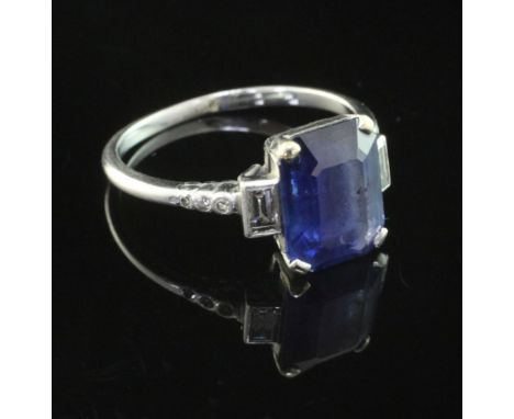 A mid 20th century platinum, sapphire and diamond ring, with diamond set shoulders and central emerald cut sapphire with the 