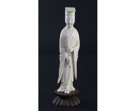 A Chinese ivory figure of a scholar, early 20th century, standing and holding a fan and a scroll in the other hand, rosewood 