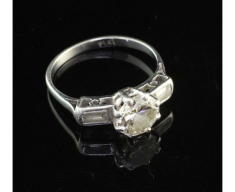 A platinum set solitaire diamond ring, with baguette cut diamond set shoulders, the round cut stone weighing approximately 1.