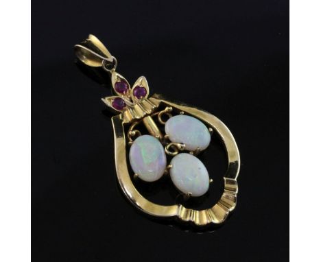 A 14ct gold, white opal and ruby pendant, set with three oval white opals, 1.25in ex. bale.