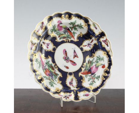 A Worcester scale blue plate, c.1770, painted with butterflies and exotic birds in gilt cartouches on a scale blue ground, bl