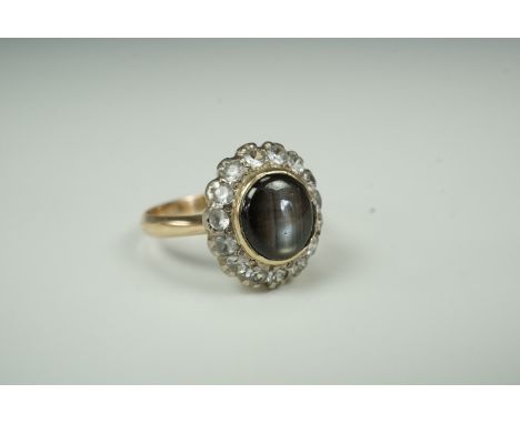 A star sapphire dress ring, the oval sapphire cabochon of approximately 7 mm x 8 mm, bezel set within a frame of brilliant-cu