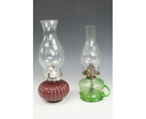 A green glass finger oil lamp together with one other,  tallest 33 cm