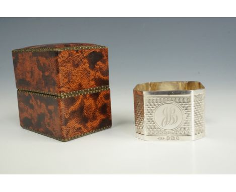 An early 20th Century silver napkin ring, of square section with canted corners, bearing engine-turned decoration, cased, 20 