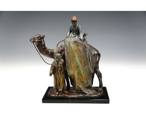A cold-painted spelter novelty figural cigarette lighter modelled as a North African selling a rug from atop a camel, mounted