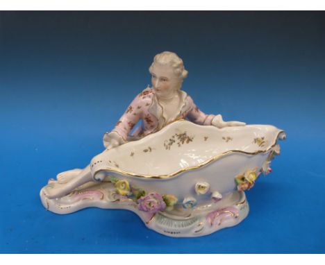 A Continental figural sweetmeat dish in the Meissen style, crossed swords over an R to base