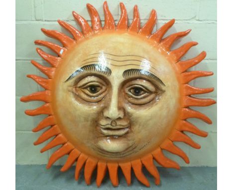 A Sergio Bustamante fibreglass model of a face in the form of the sun, limited edition 85/100, in a light beech glazed cabine
