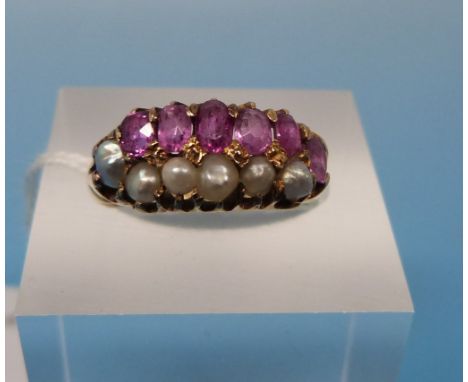 A Victorian yellow metal ring set with a row of rubies and a row of seed pearls (size K)