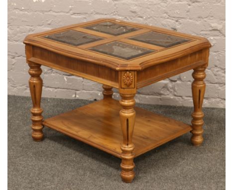 A light oak carved and turned two tier coffee table with four bevel edge glass panels.