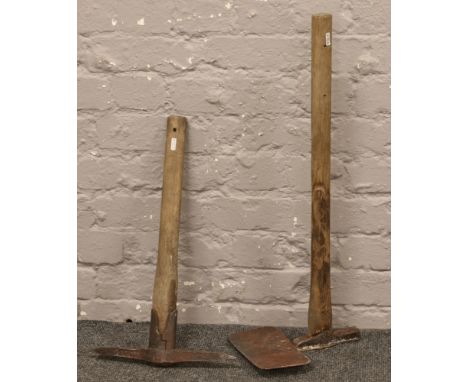 Two vintage mining related tools, a pick axe and another.