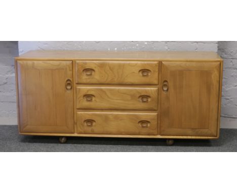 An Ercol light oak sideboard raised on easyfree casters, 156cm x 45cm x 68cm.