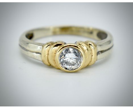 A 9ct white and yellow gold and diamond single stone ring. The hallmarked ring, partially legible with reeded shank and havin