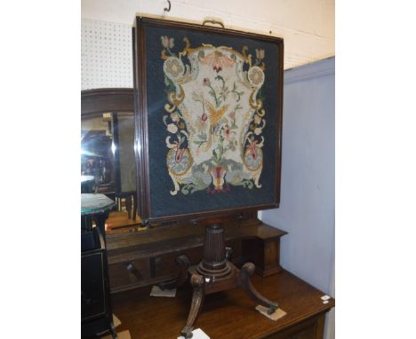An early 19th Century mahogany framed needlework tapestry panelled adjustable fire screen with rising panel and two sliding p