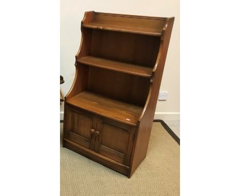 An Ercol elm side cabinet with two open shelves over two panelled cupboard doors, 61 cm wide x 33.5 cm deep x 112 cm high