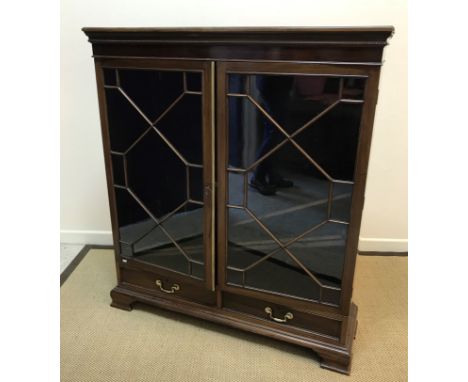 An Edwardian mahogany display cabinet, the plain top above a carved and beaded frieze and two astragal glazed doors enclosing