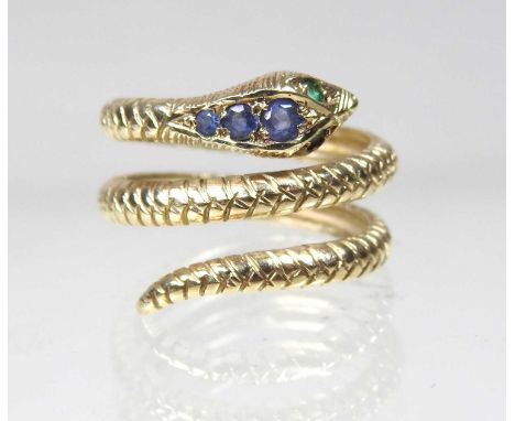 A 9 carat gold ring, in the form of a coiled snake, set with emerald eyes and having graduated sapphires to the head, size N