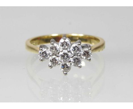 An 18 carat gold diamond cluster ring, of star shape, set with nine tiered stones, approximately 1.0 carats, size N