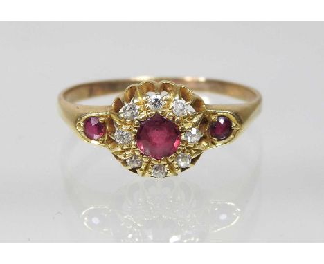 An 18 carat gold ruby and diamond target ring, with ruby set shoulders, unmarked, size S