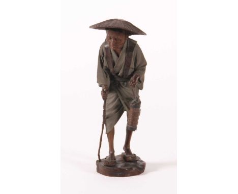 A Japanese finely carved wood figure of a gentleman, Meiji period (1868-1912), shown in standing pose wearing a wicker hat, w