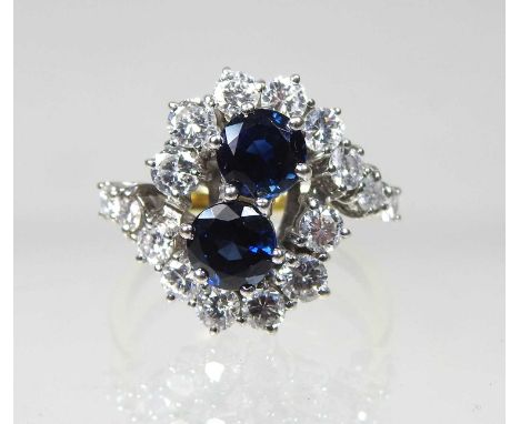 An impressive 18 carat gold sapphire and diamond cluster ring, of crossover design, set with a pair of central sapphires, app