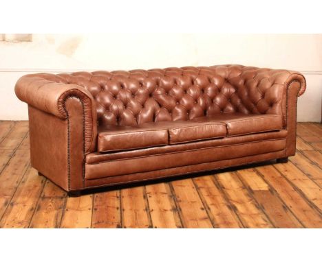 A tan leather buttoned upholstered three-seater Chesterfield sofa, contemporary, having squab cushions, brass studded detail,