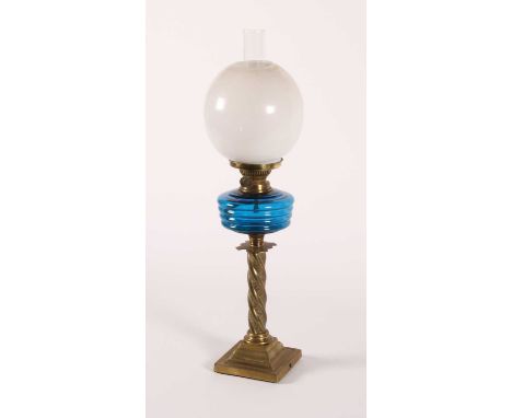 A Victorian brass oil lamp, having a blue glass font and milk glass shade upon a spiral stem, height 68cm