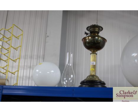 A brass oil lamp with glass chimney and milk glass shade