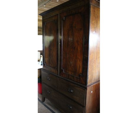 An early 19th century mahogany linen press with moulded frieze above a pair of panelled doors enclosing wardrobe, the lower p