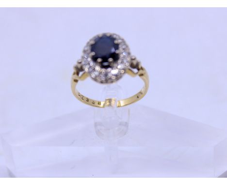 Vintage 18ct Sapphire and Diamond Cluster Ring  The Ring contains an Oval Brilliant Cut Sapphire that measures approx. 9mm x 