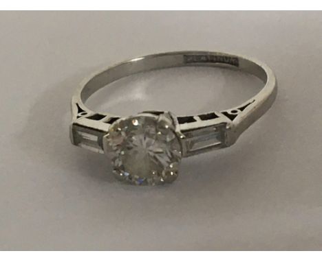 A platinum ring set with a brilliant cut diamond approximately 0.8-0.9 of a carat flanked by baguette diamonds. ring size M.