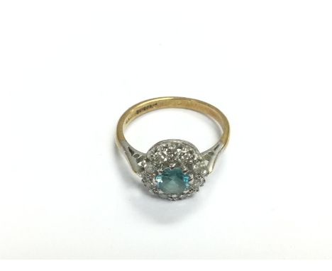 An 18ct gold ring set with a central aquamarine stone surrounded by diamonds, approx 3.6g and approx size M-N. Shipping categ