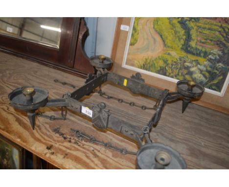 A metal four branch light fitting decorated with heraldic crests and medieval style helmets 