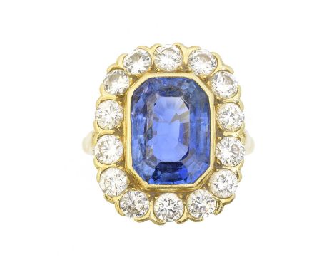 An 18ct gold sapphire and diamond cluster ring, the rectangular shape sapphire weighing approx. 6.65cts, within a brilliant c