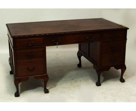 An early 20th century mahogany seven drawer pedestal desk with carved moulded top and raised on squat cabriole legs to ball a