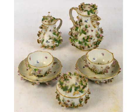 A late 19th century Meissen floral encrusted lidded jug, a similar smaller example, sugar bowl and cover and a pair of cups a