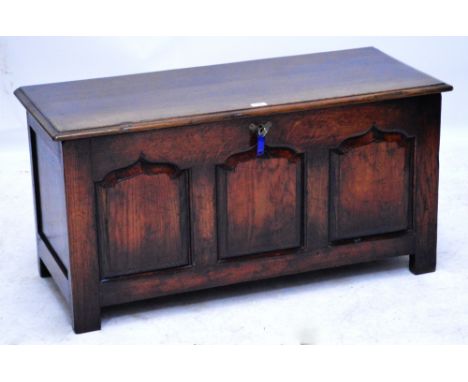 A reproduction oak coffer with hinged lid and triple fielded panel front raised on short stile supports, width 106.5cm.