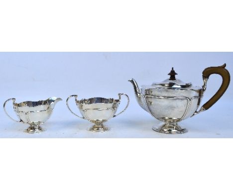 A George V hallmarked silver Art Nouveau style three piece tea set with raised panel edged decoration, organically shaped rim