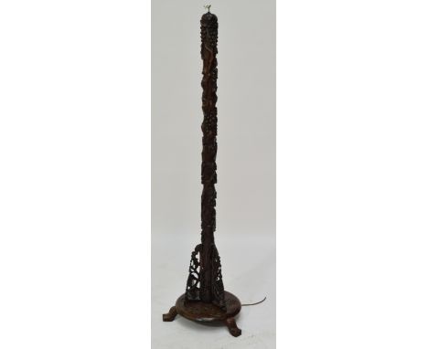 A 20th century hardwood standard lamp base carved as a trunk with fruiting vines, held by three pierced bracket above a circu