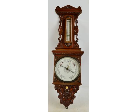 A late Victorian oak barometer with carved frame including pediment, sides and spandrels, with circular barometer gauge and t