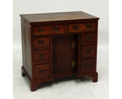 A 19th century oak small kneehole desk with eight drawers, recessed central cupboard door and raised on bracket feet.