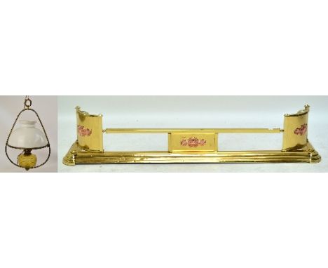 A decorative brass fender with curved rectangular base, corner panels and central panel bearing copper coloured plaques, leng
