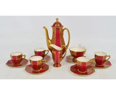 A Royal Doulton part coffee set in octagonal shape with puce background and alternate panels with gilt floral decoration, com