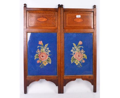 An Edwardian oak folding fire screen with inlaid shell panels to the top and glazed panels containing woolwork below, with br