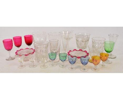 A collection of various drinking glasses including a set of seven liqueur glasses in green, orange, blue and clear glass, a s