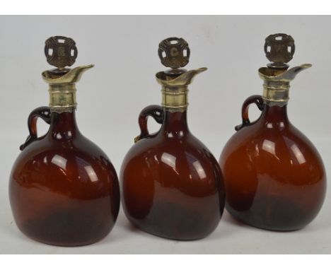 A set of three dark amber glass spirit decanters of flat globular form with loop handles and electroplated mounts with modell