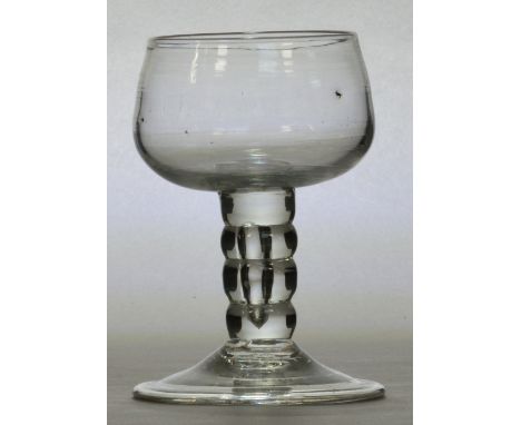 An early 18th century champagne glass with squat bowl above unusual bobbin turned stem and folded foot, English c.1735, heigh