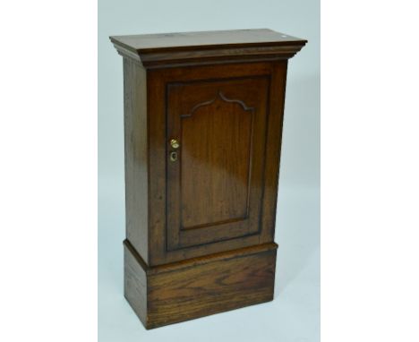 A 19th century oak cupboard with hinged panel door in a shaped frame enclosing two shaped shelves, with cornice top and deep 