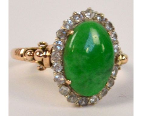 A 14ct yellow gold and jade dress ring, the polished oval stone surrounded by tiny clear stones (one missing), with ball and 