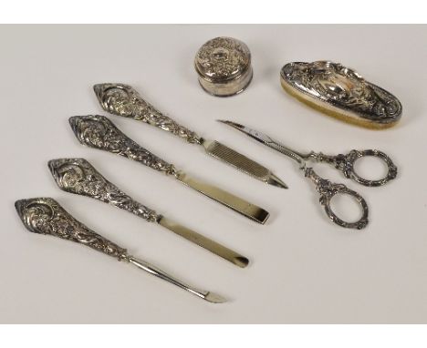 A cased Edwardian hallmarked silver manicure set, comprising small cylindrical pot, buffer, scissors and four silver sheath h