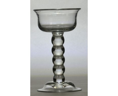 An early 18th century champagne glass with ogee bowl above unusual bobbin turned stem and domed foot, English c.1735, height 